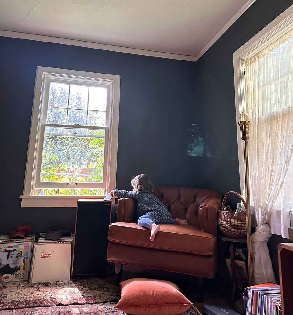 A young girl on a leather chair playing with a coaster.